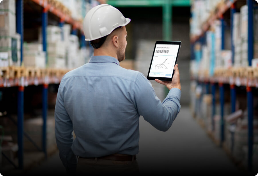 A man standing in a warehouse holding a tablet